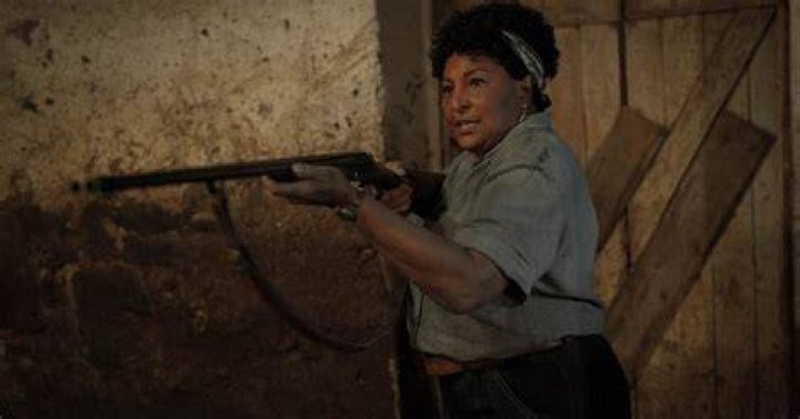 Marjorie (portrayed by Pam Grier) holding a gun to something off-screen.